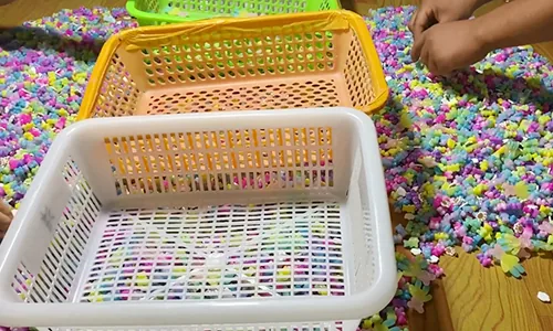 Worker sorting colorful decorative craft pieces
